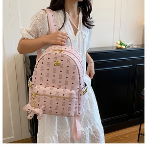 Détail d'un sac à dos rose à motifs de dessins animés avec plaque et ours en peluche