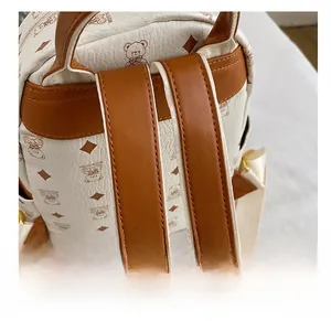Detail of white litchi pattern leather straps with bear print and golden buckles