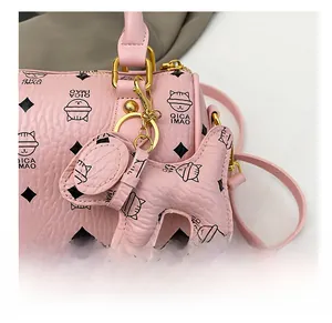 Detail of pink cylinder bag showing textured faux leather and cute cat head charm