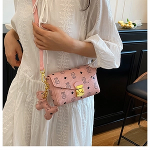 Détail du sac enveloppe rose avec imprimé chat, fermoir doré et accessoire chiot