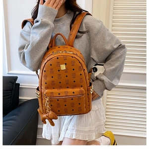 Dettaglio dello zaino cognac con stampa monogramma vintage e placca logo in metallo dorato