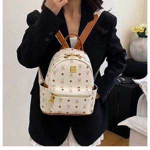 Close-up of mini cream backpack with brown bear pattern and gold bear charm detail