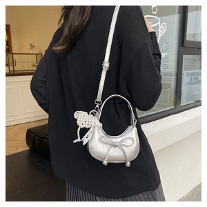 Silver crescent shoulder bag with large bow and pearl charm on a female model