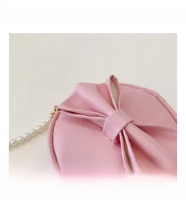 Détail du sac rond rose pour enfant avec nœud et élégante bandoulière en perles