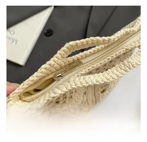 Close-up of golden metal zipper and intricate knit texture on a beige handmade woven bag