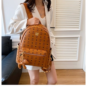 Détail d'un sac à dos marron à monogramme avec plaque dorée et charm chien en cuir
