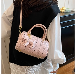 Detail of pink Boston bag featuring cute cat print and a small dog charm on a model