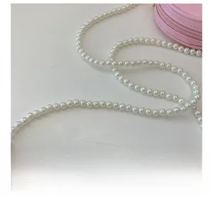 Détail de la bandoulière élégante en perles sur un petit sac à bandoulière rose rond