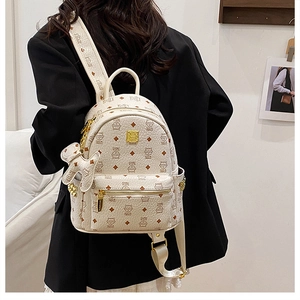Dettaglio mini zaino beige in pelle con ciondolo a forma di orso e stampa monogram
