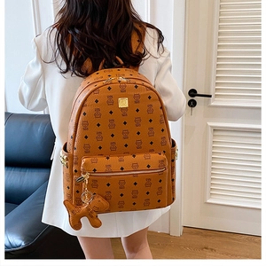 Détail d'un sac à dos marron à motifs avec plusieurs poches et un charm en forme de chien