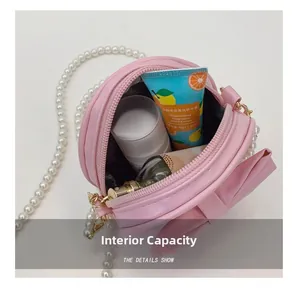 Détail montrant la capacité interne du mini sac à bandoulière rond rose avec nœud