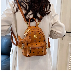 Detailed close-up of brown PU leather mini backpack with bear print and dog charm