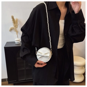 Détail d'un sac rond blanc pour fille avec nœud et bandoulière en perles chic