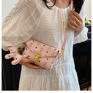 Vue détaillée du sac bandoulière rose avec imprimé chat et breloque ours sur un mannequin