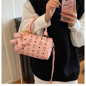 Detailed side view of pink kitty print boston bag with bear charm and long strap