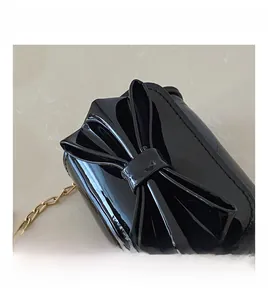 Detailed macro view of the glossy black patent leather material and oversized bow ornament