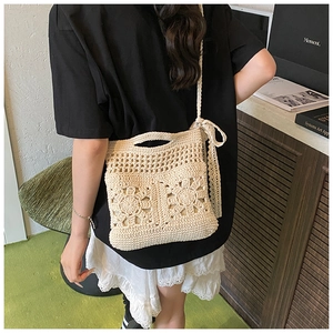 Close-up of cream handmade crochet bag featuring floral cutouts and delicate lace bow