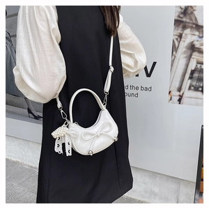 White leather crescent bag with bow detail and pearl lace pendant shown on a model