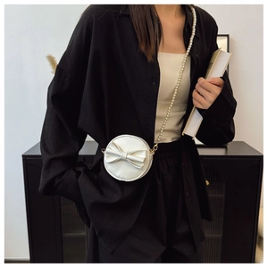 Détail du mini sac rond blanc avec nœud décoratif et élégante bandoulière perlée