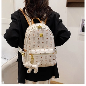 Dettaglio dello zaino beige con motivo di orsetto e cerniere dorate sul modello