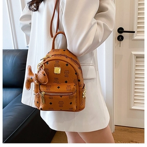 Close-up of caramel mini backpack with monogram print and cute plush bone pendant