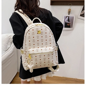 Détail du sac à dos crème avec imprimé chat, finitions dorées et breloque chien