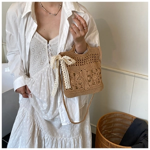 Detail of crochet shoulder bag featuring floral cutout patterns and white lace bow decoration