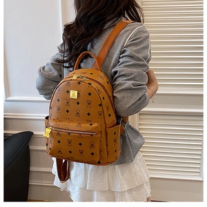 Detail view of brown backpack with cute bear pattern and golden logo plate on the front