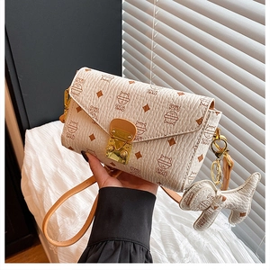 Détail de la pochette crème avec imprimé chat, fermoir doré et breloque petit chien