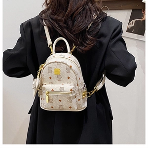 Detail of white faux leather backpack with cat monogram print and gold metal zippers