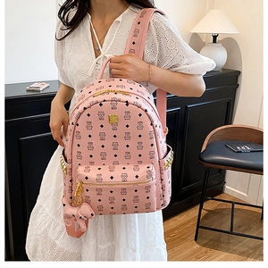 Détail du sac à dos rose avec imprimé logo, clous dorés et pendentif éléphant mignon
