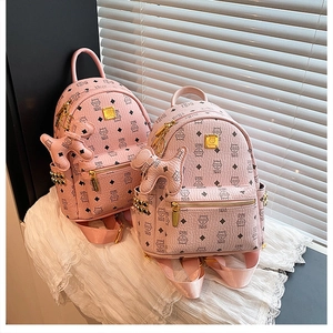 Dettaglio degli zaini mini rosa con ciondolo a forma di cane e borchie metalliche