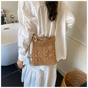 Detail of hand-woven crossbody straw bag with 3D crochet flowers and lace bow accent
