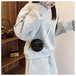 Sac rond noir pour fille avec nœud décoratif et bandoulière en perles porté par mannequin