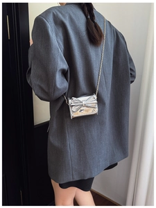 Close-up of silver bow crossbody bag with metallic finish and delicate gold chain strap