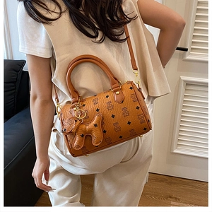 Brown Boston bag with monogram pattern and dog charm shown worn as a crossbody bag