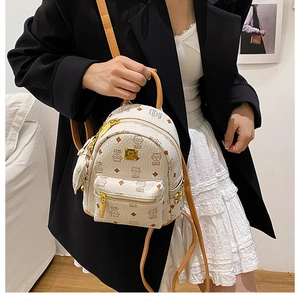 Detail of mini cream backpack featuring cartoon cat prints and gold metal brand plaque