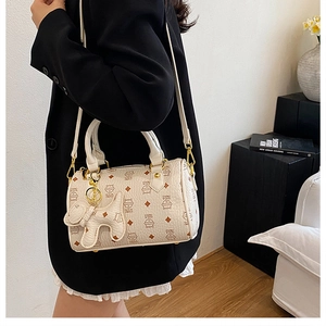 Detail view of cream Boston bag with cute cat prints and a decorative puppy charm