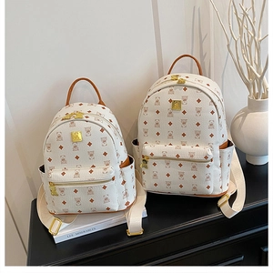 Detail view of cream bear print backpacks in large and small sizes on a modern black cabinet