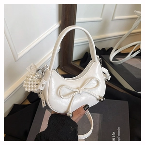 Detail of white crescent mini bag with ribbon bow and elegant pearl ball charm