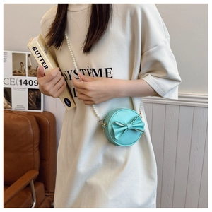 Détail du mini sac rond vert menthe avec nœud doux et chaîne en perles blanches
