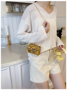Detail showing shiny gold patent leather mini bag with bow accent and chain strap