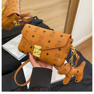 Détail du sac en cuir marron avec imprimé chat et pendentif doré en forme de chien