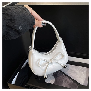 Detail of white half-moon bag featuring a bow with silver metallic beads and zipper