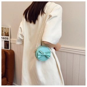 Détail du mini sac rond vert menthe avec nœud 3D et élégante bandoulière en perles