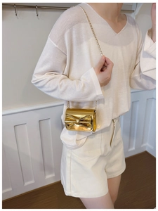 Close-up of golden metallic mini crossbody bag with bow detail on a child model
