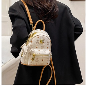 Side view of cream mini backpack with bear print and brown leather straps on a black blazer
