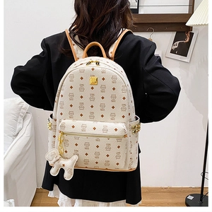 Détail du sac à dos beige à imprimé chat avec clous en métal et charmant petit chien blanc