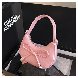 Detail view of pink crescent bag featuring crocodile texture and leather bow decoration