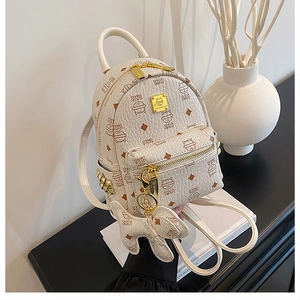 Detail of mini backpack showing lychee grain leather texture and metallic logo plaque